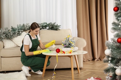 Photo of Woman from cleaning service working in messy room after New Year party