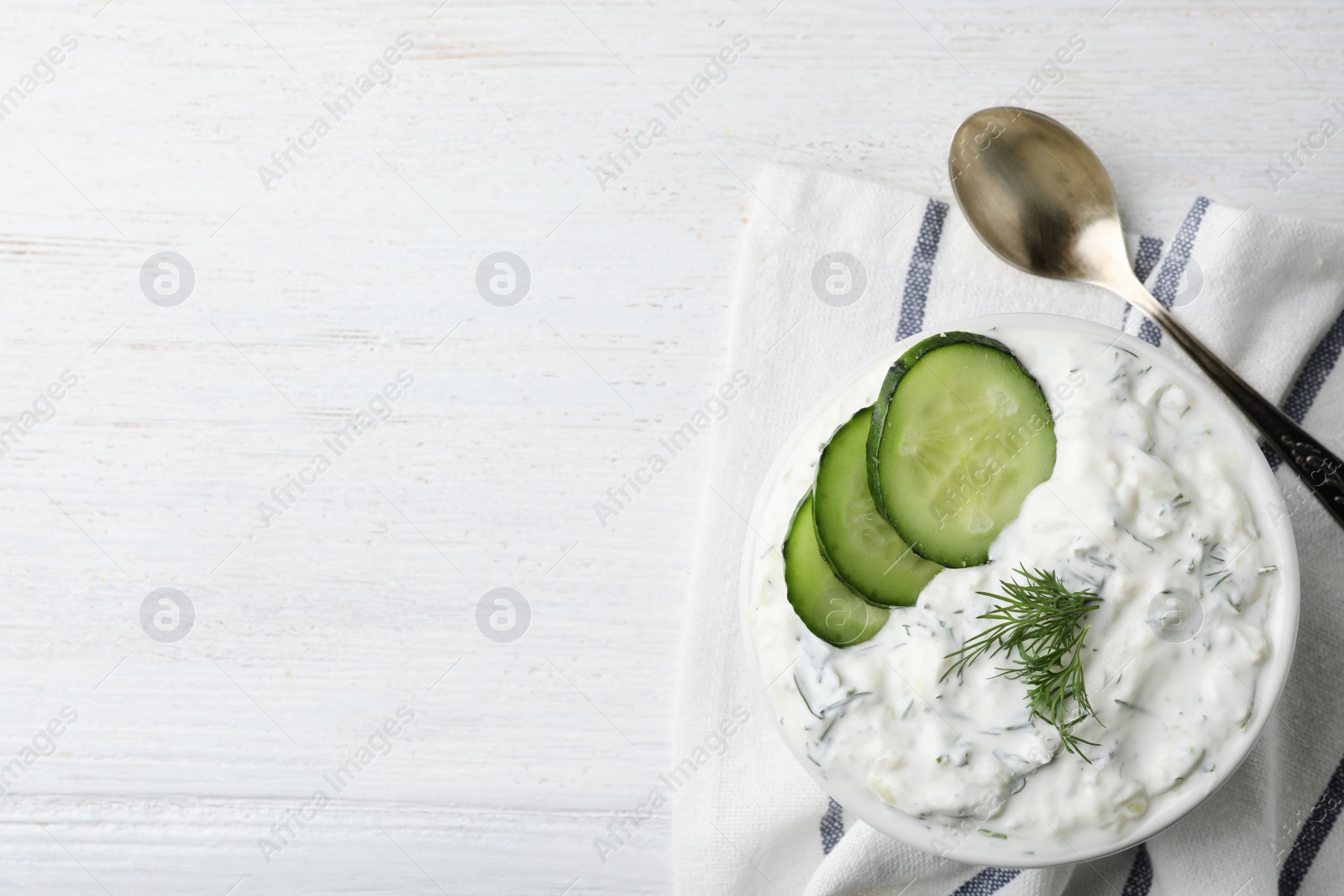 Photo of Cucumber sauce, spoon and space for text on wooden background, flat lay. Traditional Tzatziki