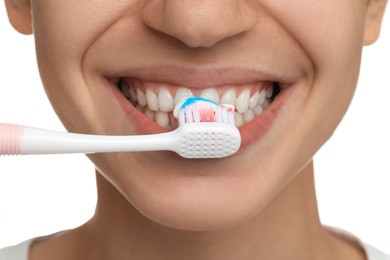 Photo of Woman brushing teeth with paste on white background, closeup. Dental care