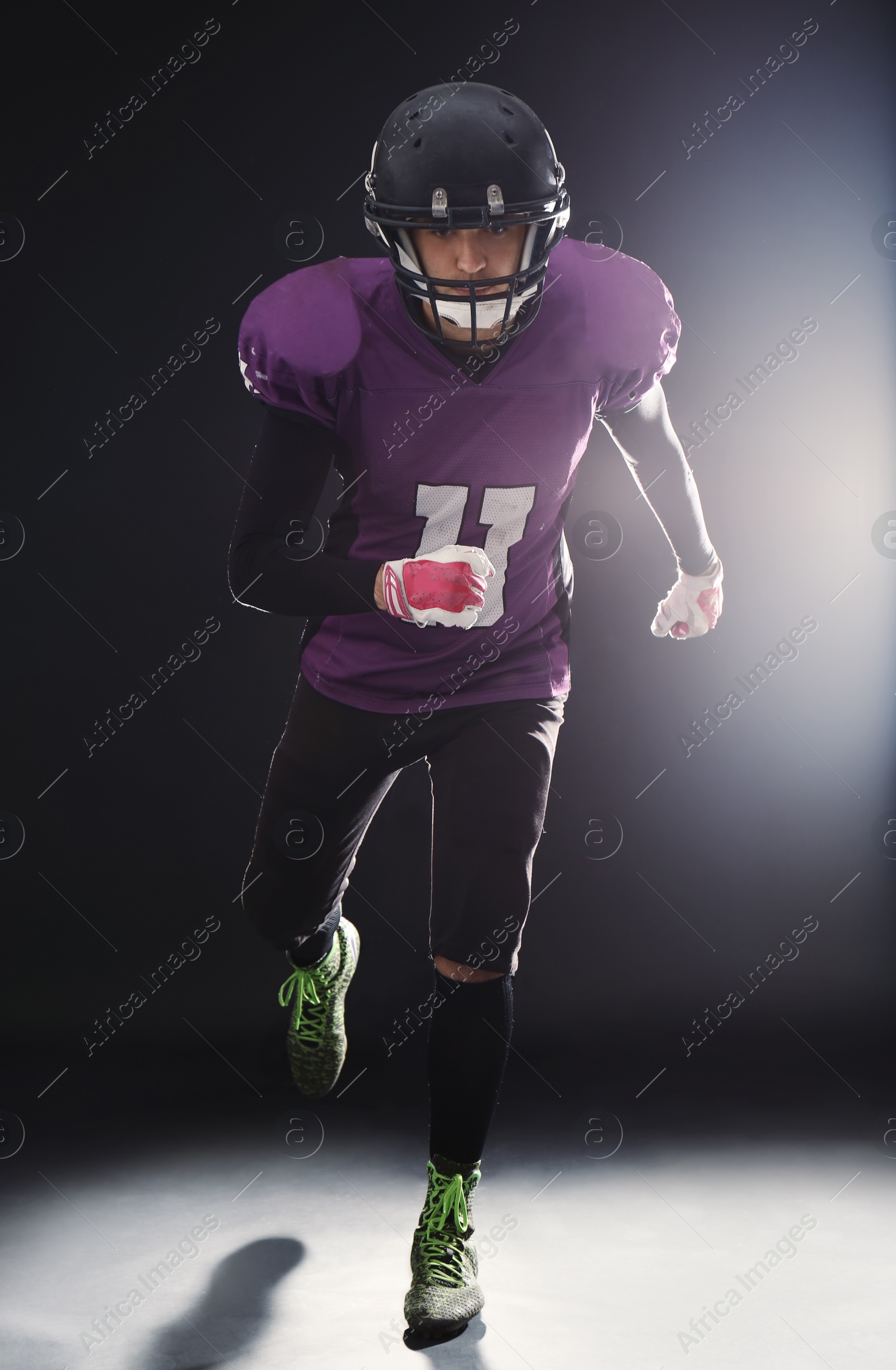 Photo of American football player wearing uniform on dark background