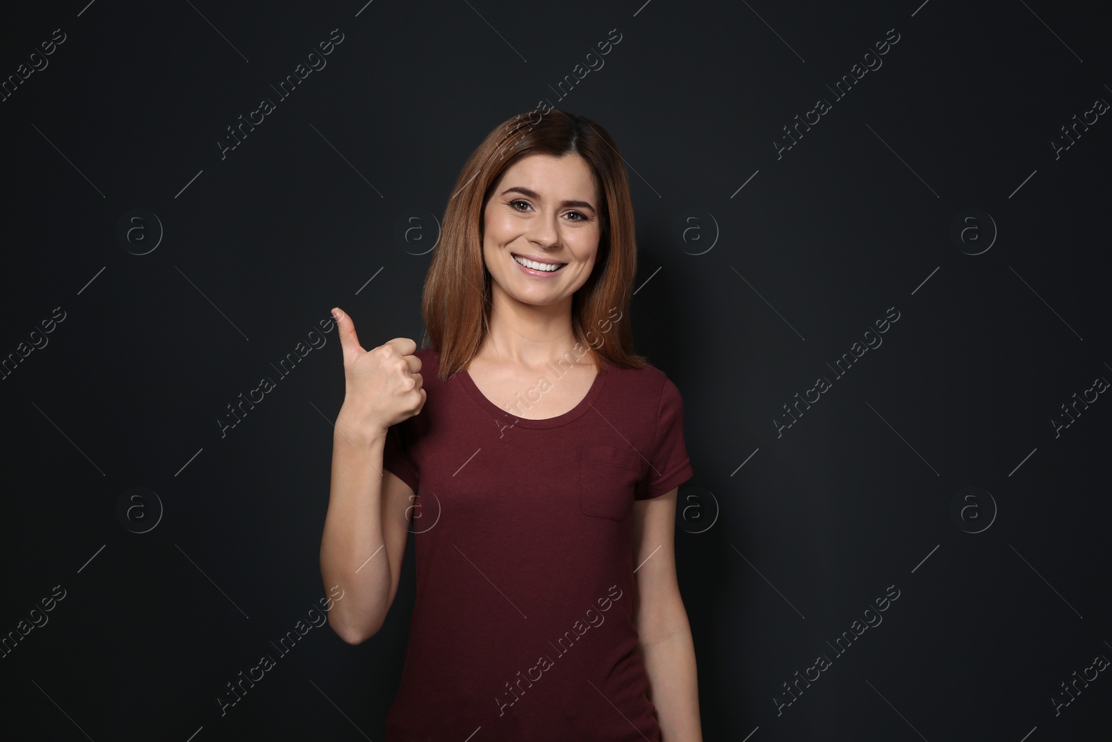 Photo of Woman showing THUMB UP gesture in sign language on black background