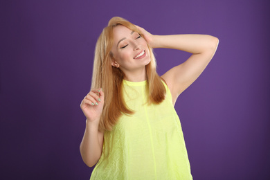 Photo of Beautiful young woman with blonde hair on purple background