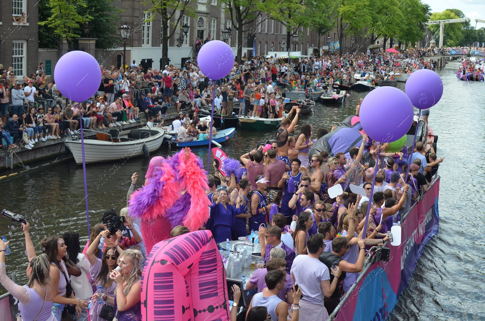 Photo of AMSTERDAM, NETHERLANDS - AUGUST 06, 2022: Many people in boats at LGBT pride parade on river