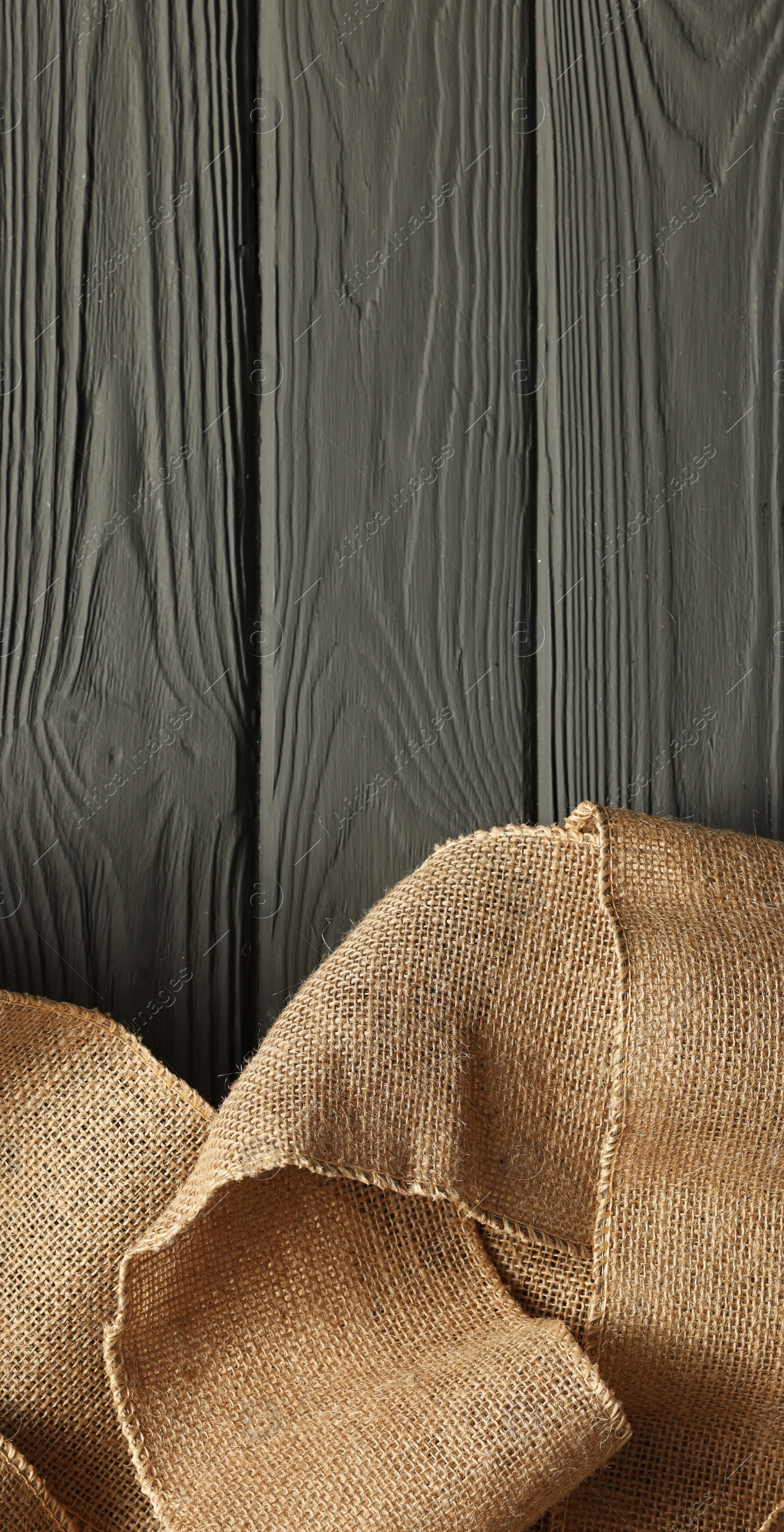 Photo of Pieces of burlap fabric on grey wooden table, top view. Space for text