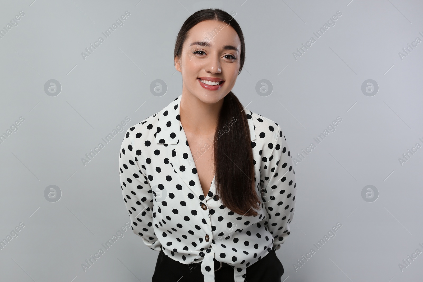 Photo of Portrait of beautiful young woman in polka dot blouse on light grey background