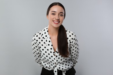 Portrait of beautiful young woman in polka dot blouse on light grey background