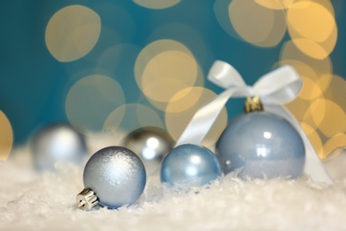 Photo of Beautiful blue Christmas balls on snow against blurred festive lights