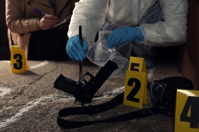 Investigator and criminologist working at crime scene outdoors, closeup
