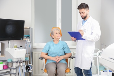 Photo of Senior woman visiting otolaryngologist in clinic. Hearing aid