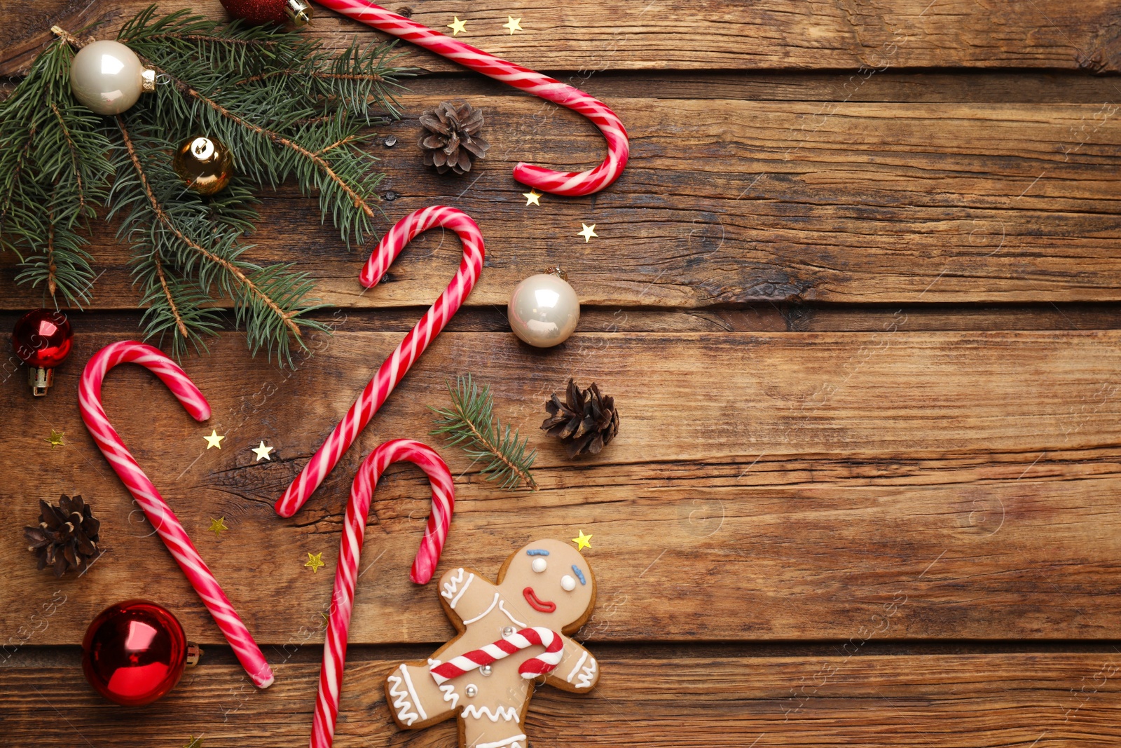 Photo of Flat lay composition with tasty candy canes and Christmas decor on wooden table, space for text