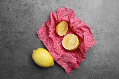 Photo of Whole and cut fresh lemons with beeswax food wrap on grey table, flat lay
