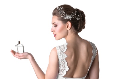 Beautiful young bride with bottle of perfume on white background