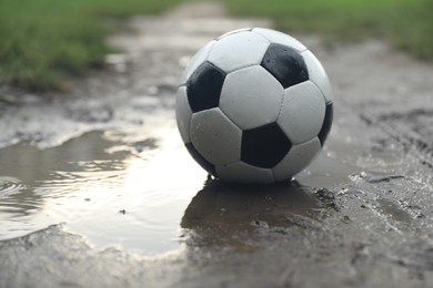 Photo of Dirty leather soccer ball in puddle outdoors