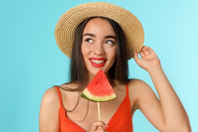 Beautiful young woman posing with watermelon on color background