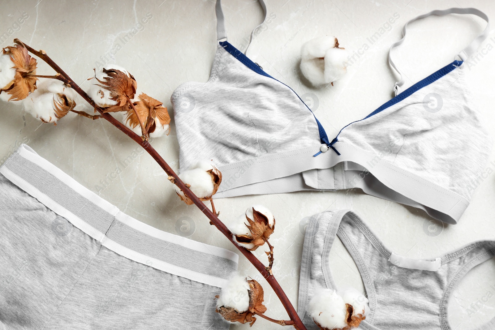 Photo of Sports women's underwear and cotton flowers on light grey marble background, flat lay