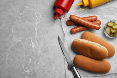 Different tasty ingredients for hot dog on light grey marble table, flat lay. Space for text