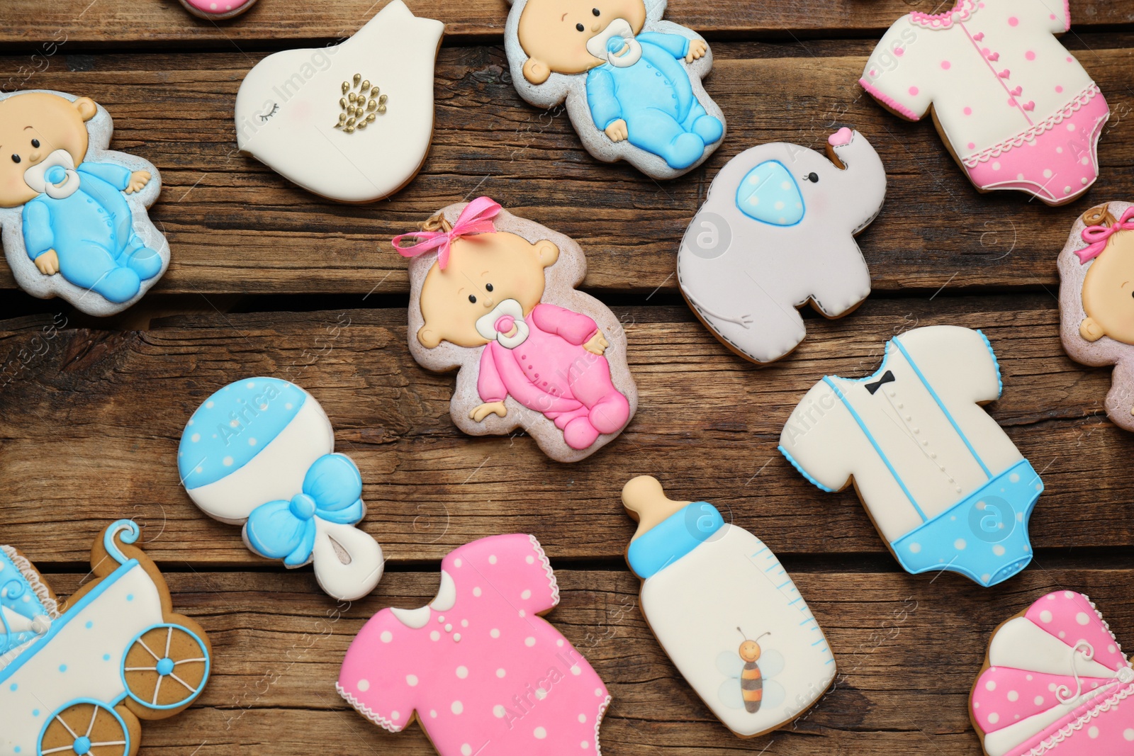 Photo of Cute tasty cookies of different shapes on wooden table, flat lay. Baby shower party