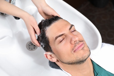 Photo of Stylist washing client's hair at sink in beauty salon