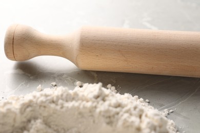 Pile of flour and rolling pin on grey marble table, closeup