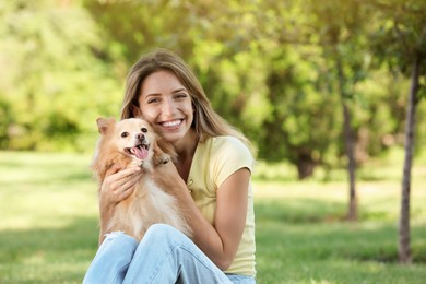 Young woman with her cute dog in park, space for text