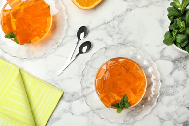 Photo of Flat lay composition with orange jelly in  bowls on marble table