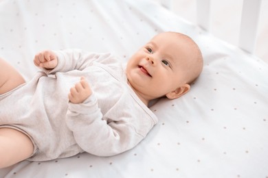 Photo of Cute little baby lying in crib at home