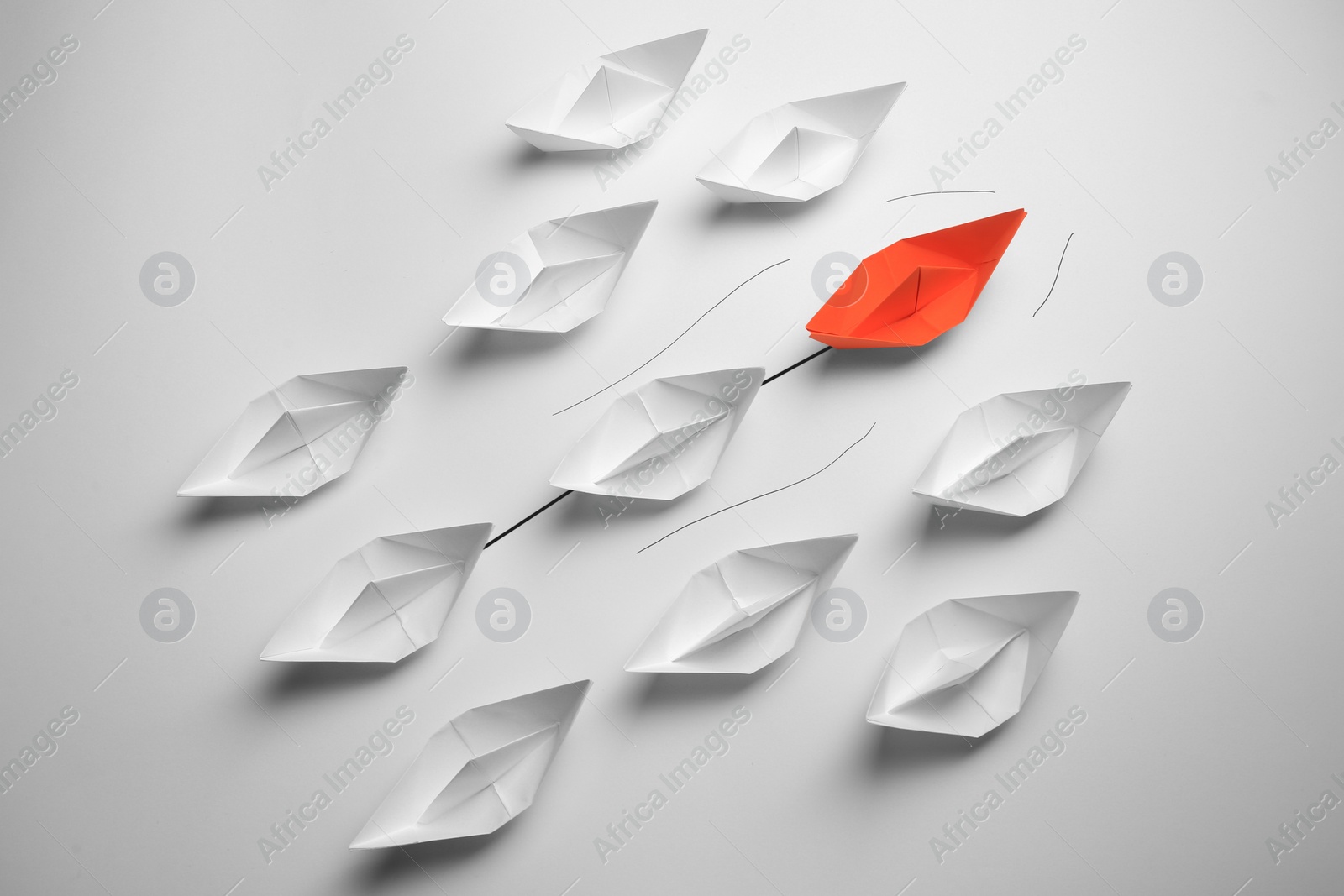 Photo of Group of paper boats following orange one on white background. Leadership concept