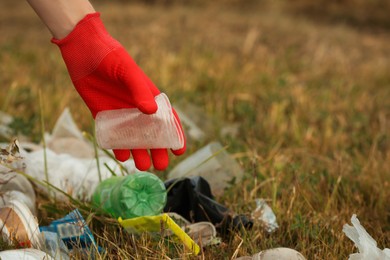 Photo of Woman in gloves collecting garbage in nature, closeup
