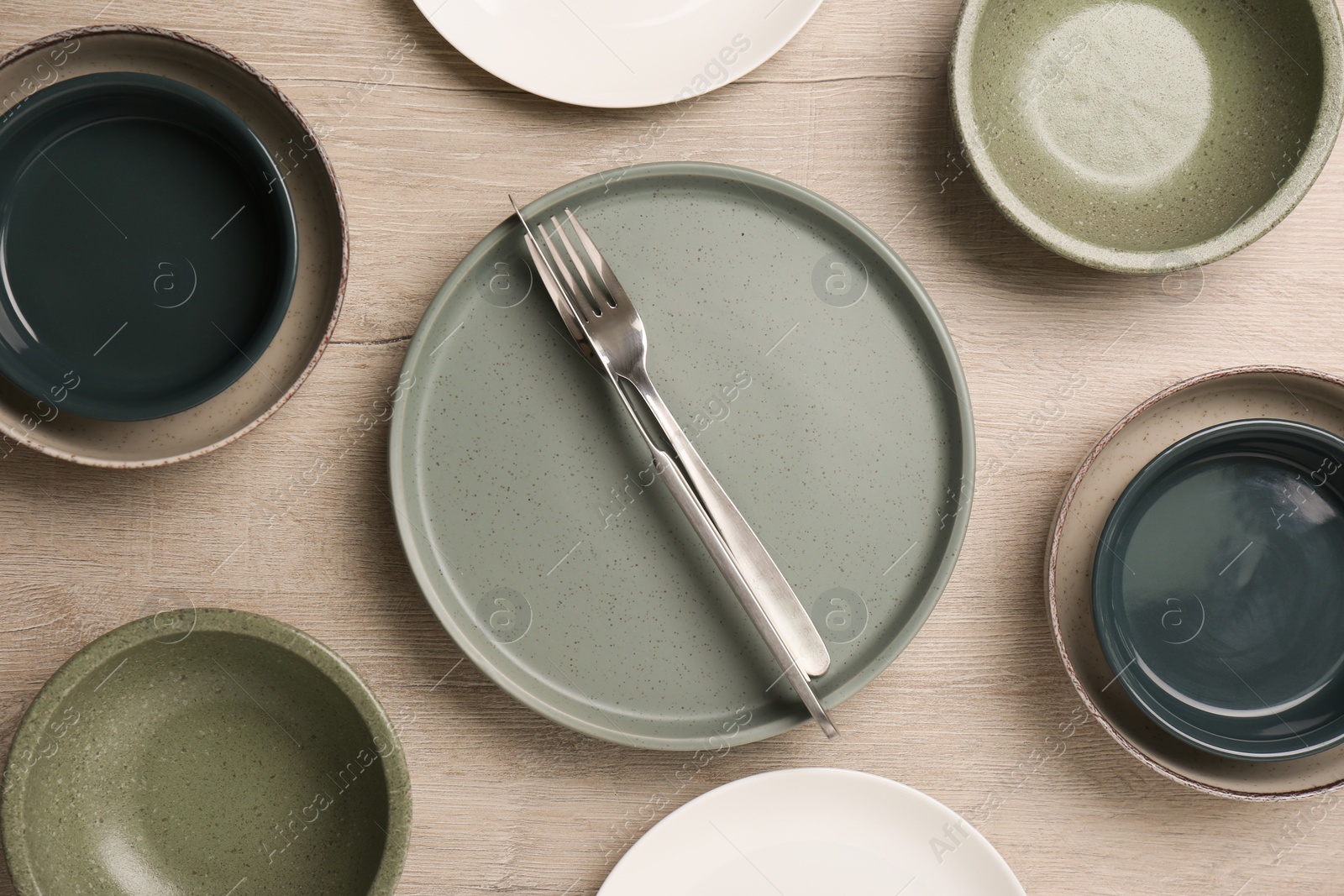 Photo of Different plates, bowls and cutlery on wooden table, flat lay