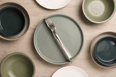 Photo of Different plates, bowls and cutlery on wooden table, flat lay