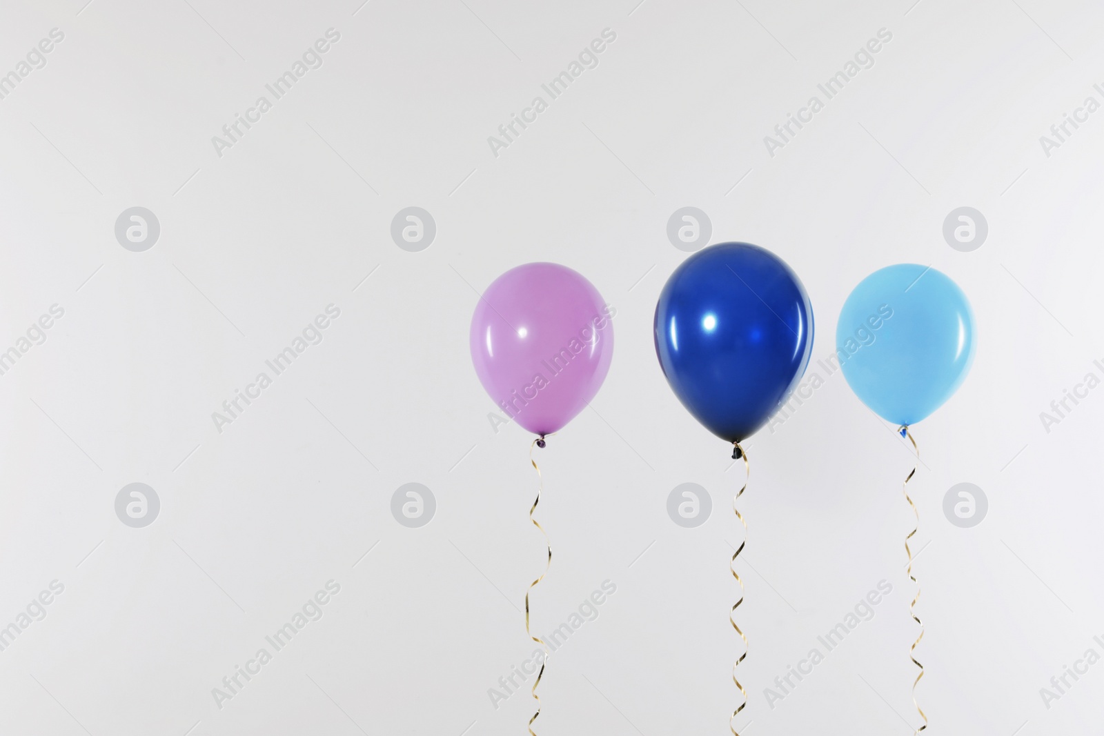 Photo of Different bright balloons on light background, space for text. Celebration time