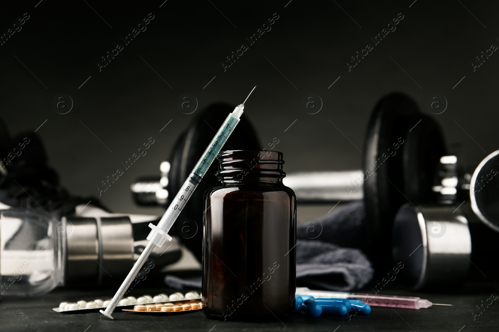 Photo of Different drugs near sports equipment on black table. Doping control