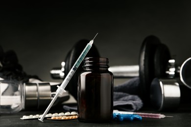 Photo of Different drugs near sports equipment on black table. Doping control