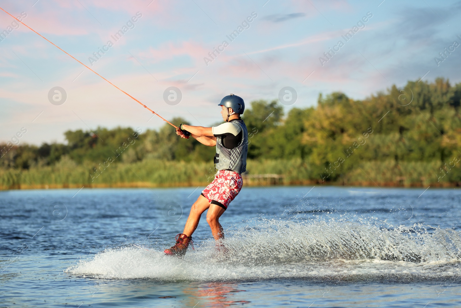 Photo of Teenage boy wakeboarding on river. Extreme water sport