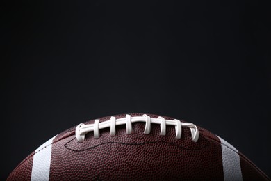 Photo of American football ball on black background, closeup. Space for text