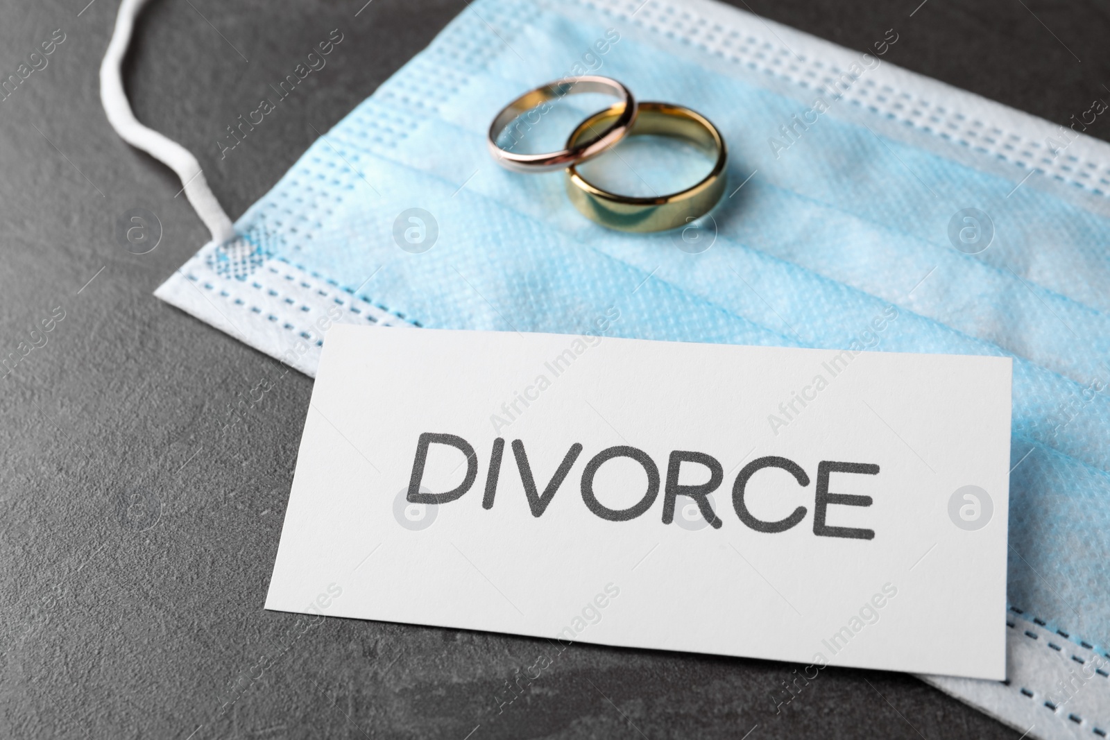 Photo of Composition protective mask and wedding rings on grey table. Divorce during coronavirus quarantine