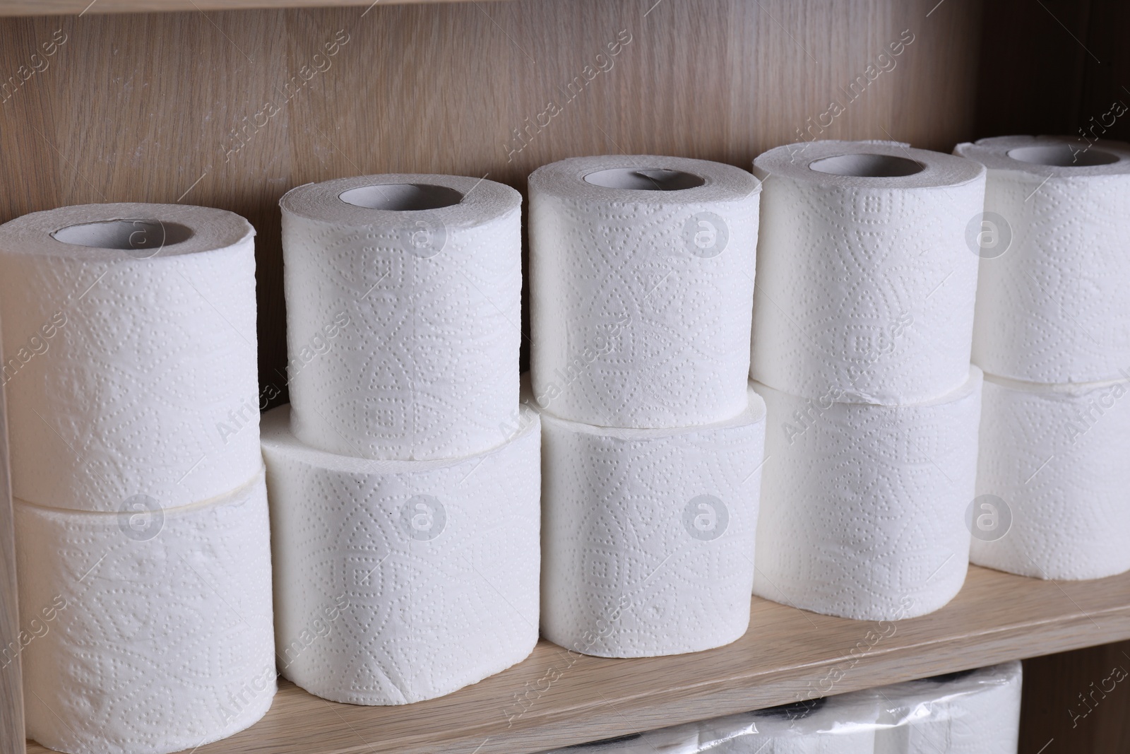 Photo of Stacked toilet paper rolls on wooden shelf