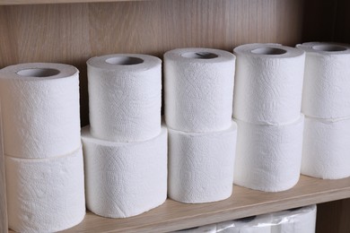 Stacked toilet paper rolls on wooden shelf