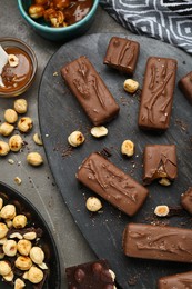 Photo of Delicious chocolate candy bars with caramel and nuts on grey table, flat lay