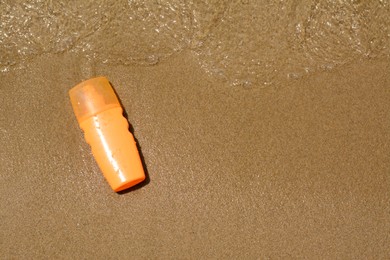 Photo of Bottle with sun protection spray near sea, top view. Space for text