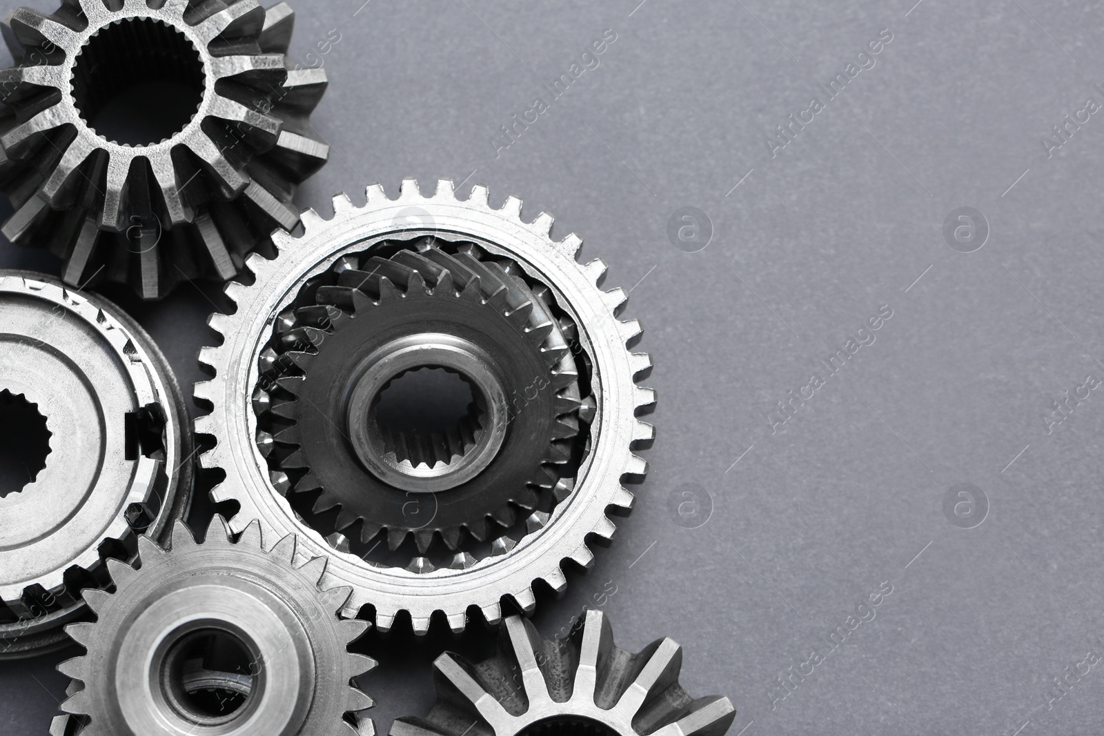 Photo of Many different stainless steel gears on grey background, flat lay. Space for text