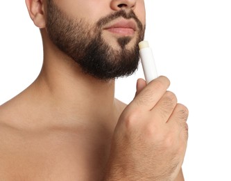 Photo of Young man applying lip balm on white background, closeup