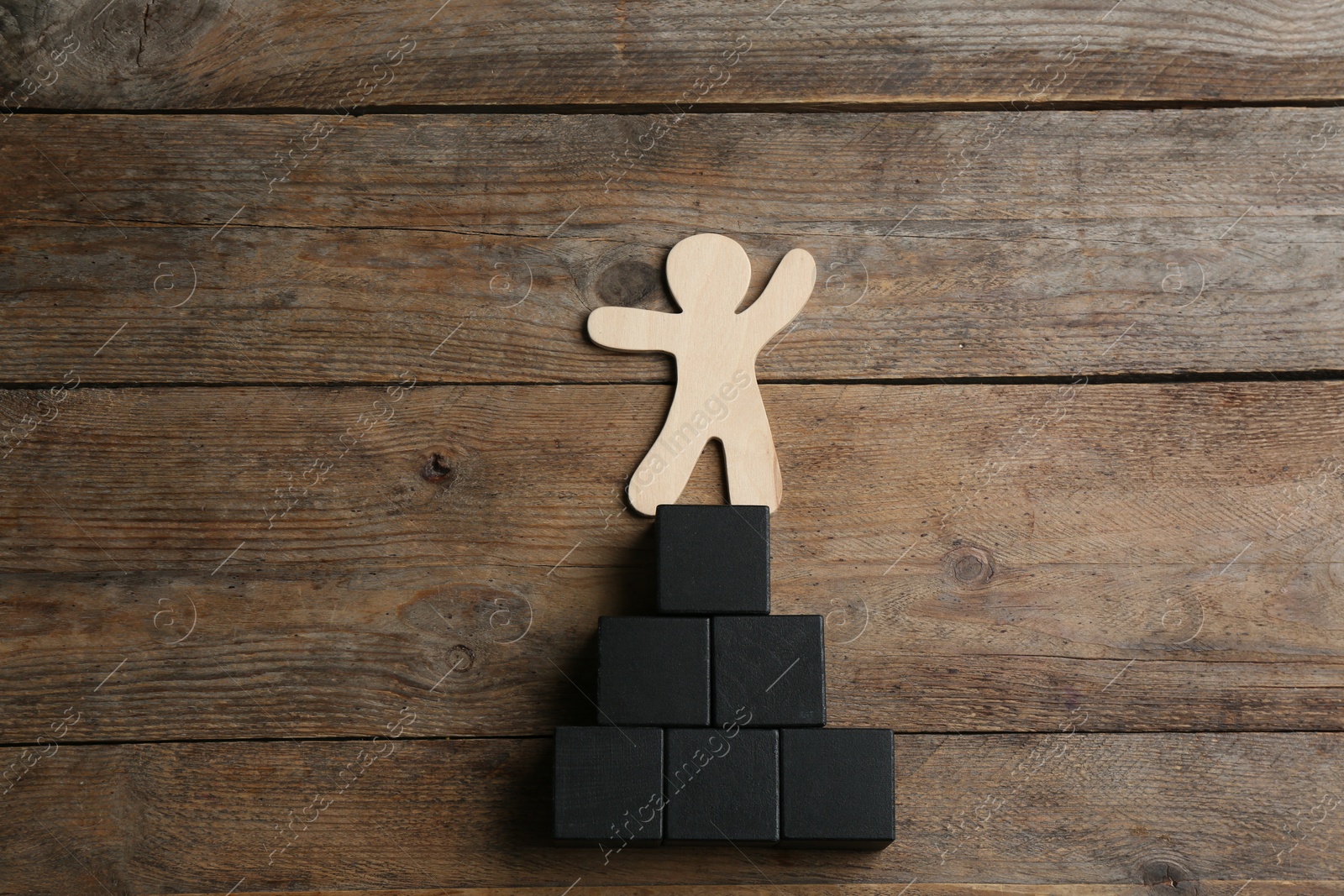 Photo of Human figure and pyramid on wooden background, flat lay. Career promotion concept