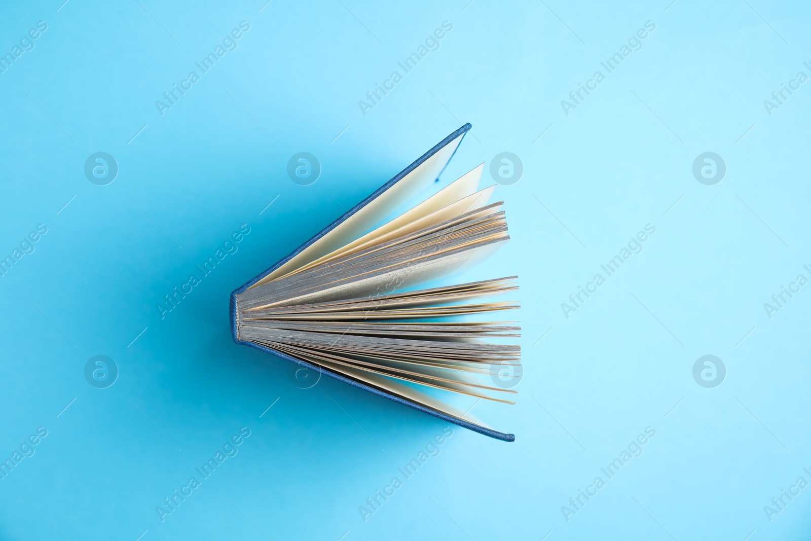 Photo of Hardcover book on light blue background, top view