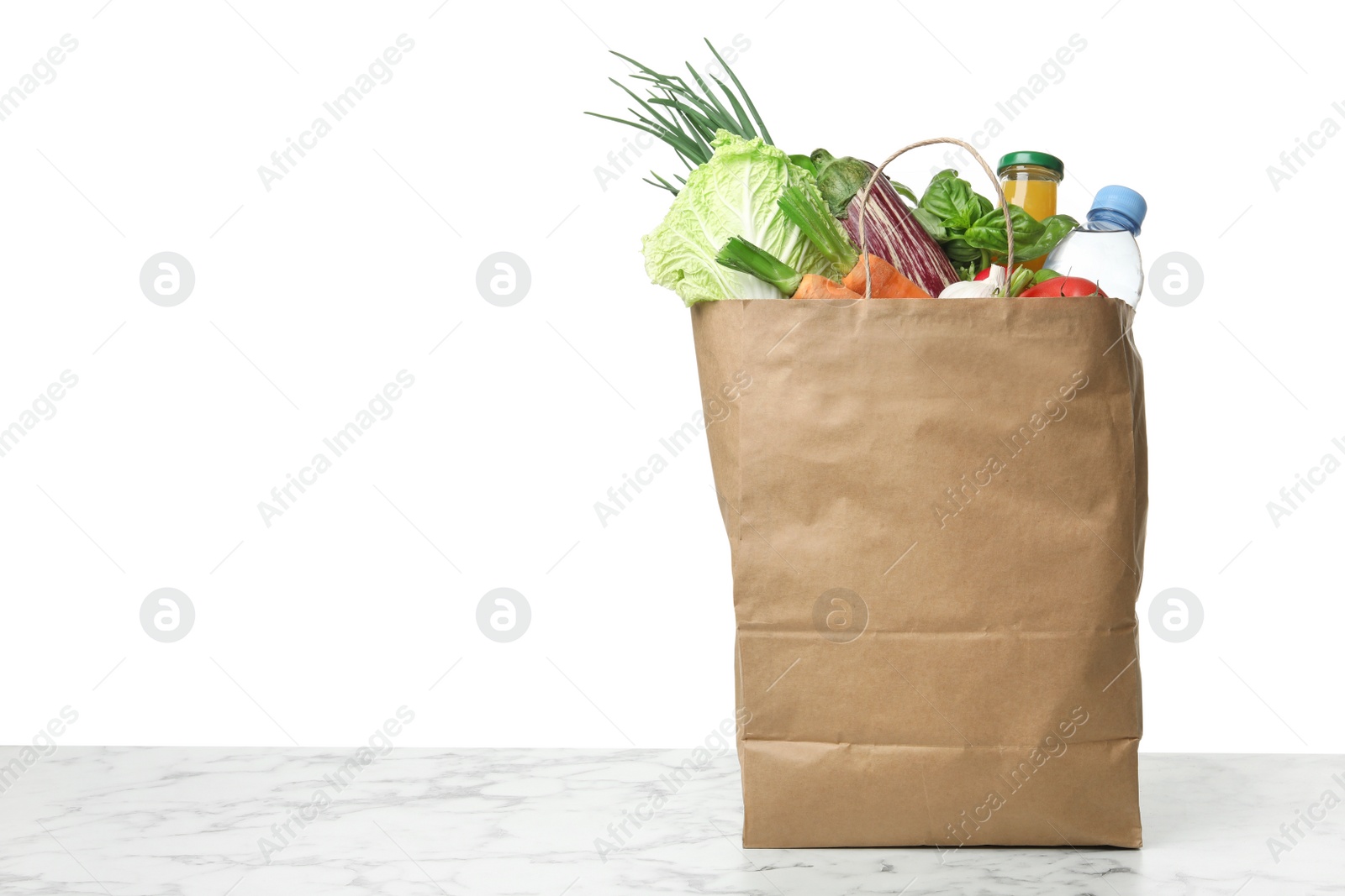 Photo of Paper bag with vegetables on table against white background. Space for text