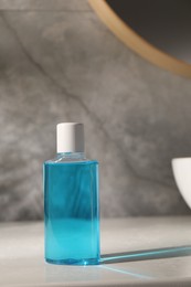 Photo of Bottle of mouthwash on light table in bathroom