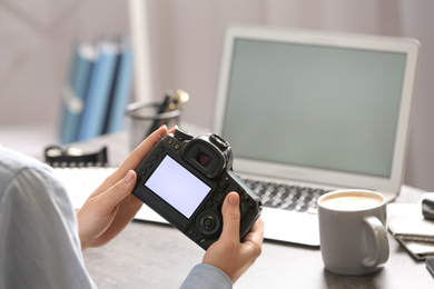 Journalist with camera at table in office, closeup