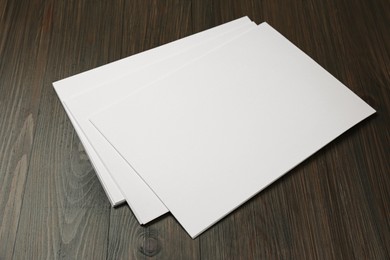 Photo of Stack of blank paper sheets on wooden table. Brochure design