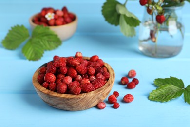 Fresh wild strawberries in bowl on light blue table