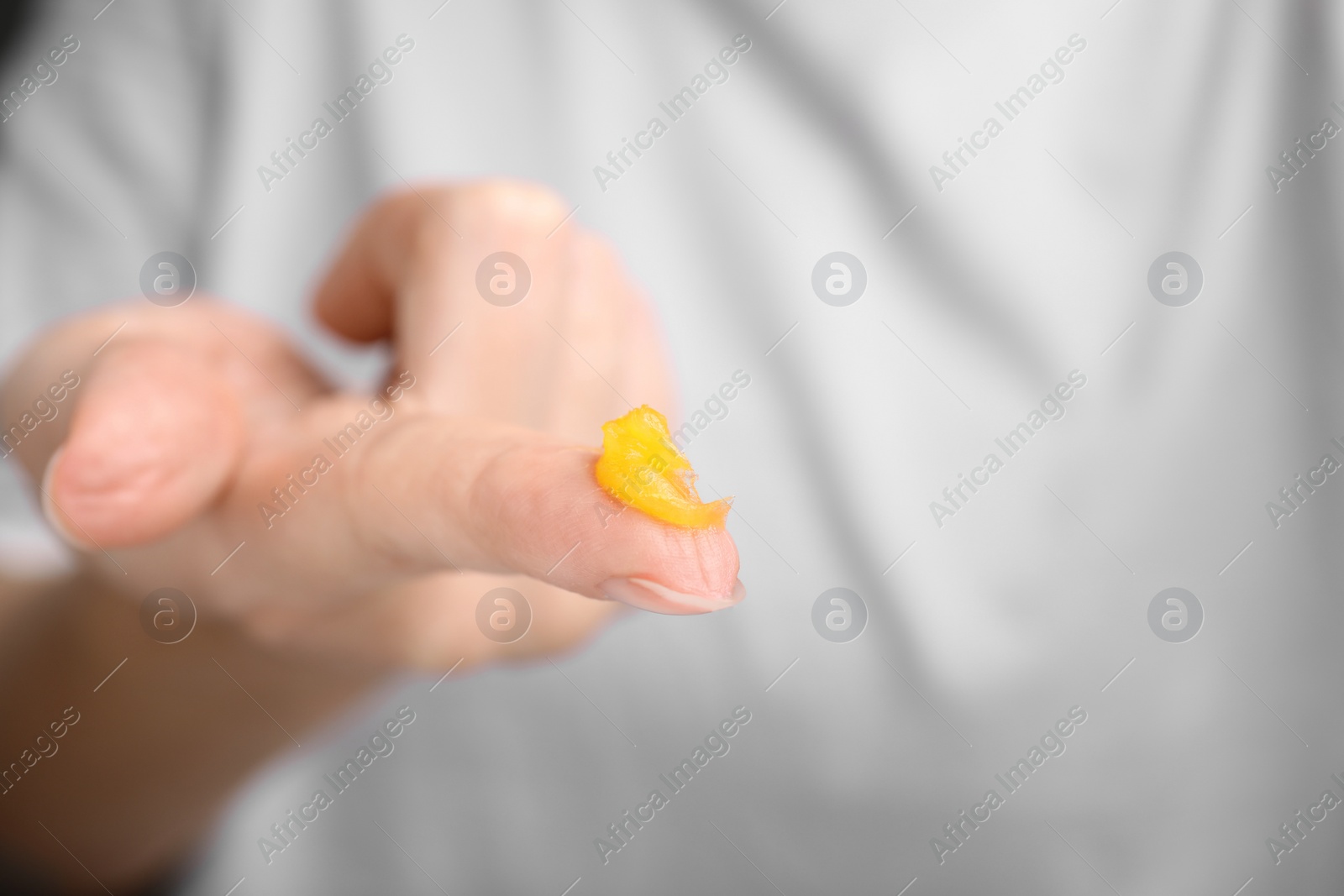 Photo of Woman with sample of cosmetic petrolatum on her finger, closeup. Space for text